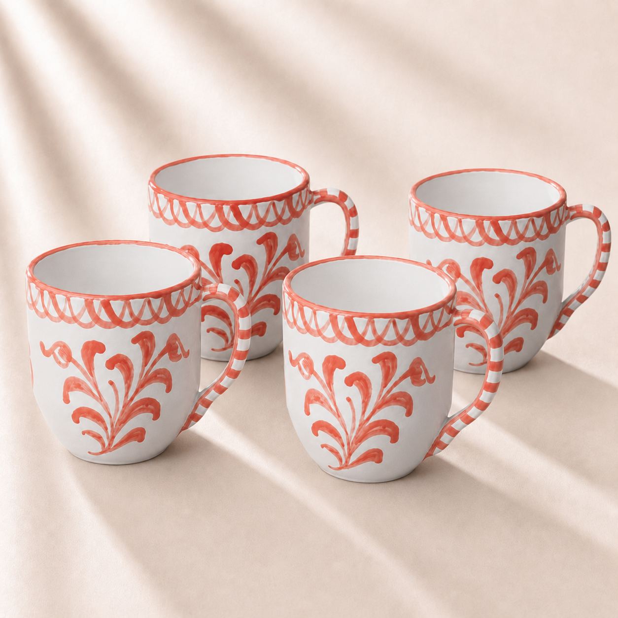 Four white mugs with orange floral patterns on a beige background