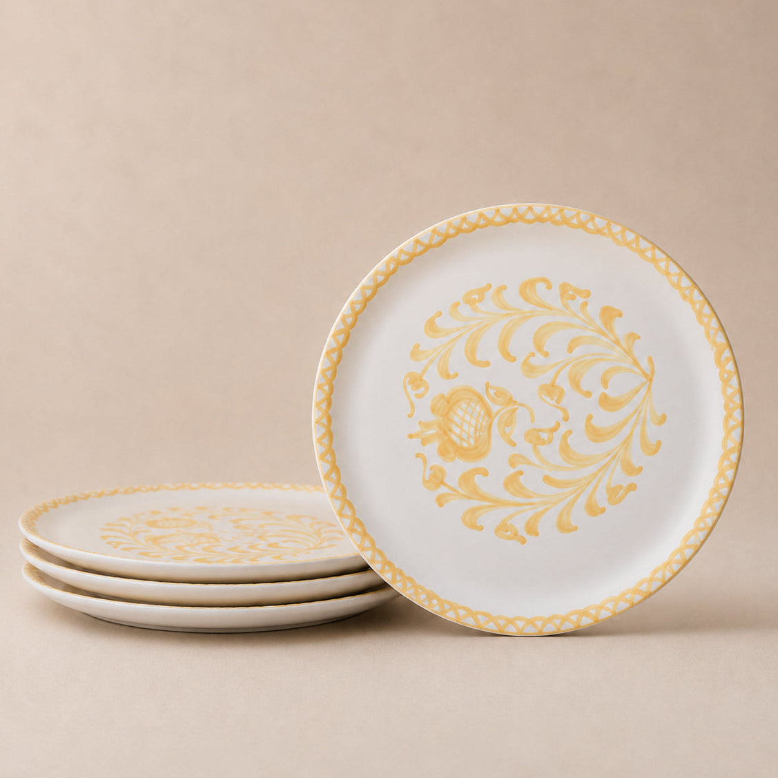 Set of white plates with gold decorative patterns on a beige background