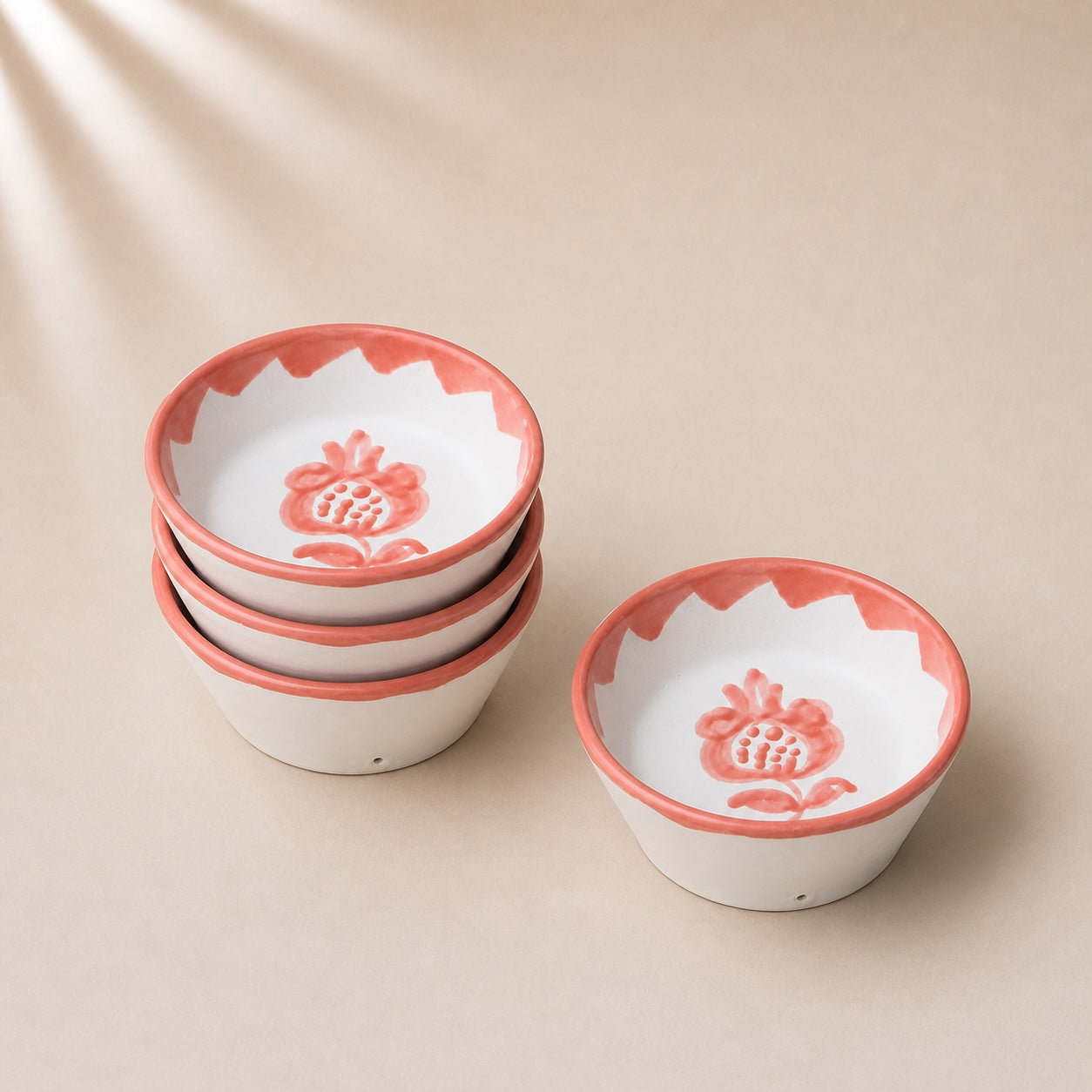 Set of ceramic bowls with red rims and floral designs on a beige background