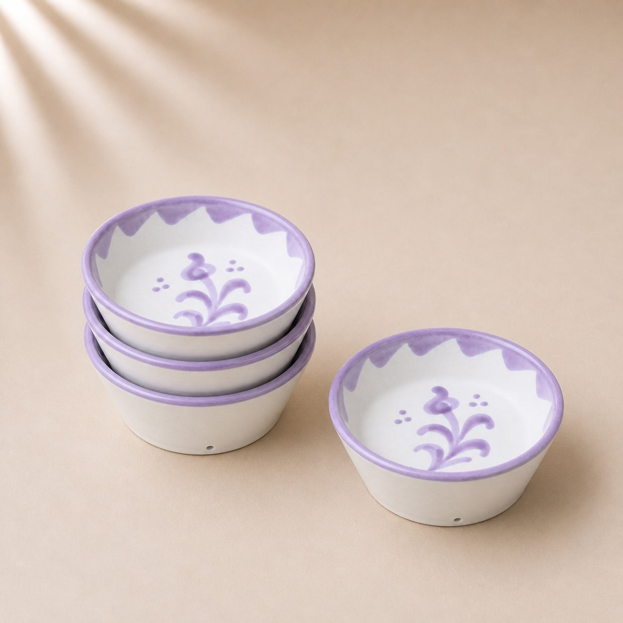 Set of ceramic bowls with purple floral patterns on a beige background