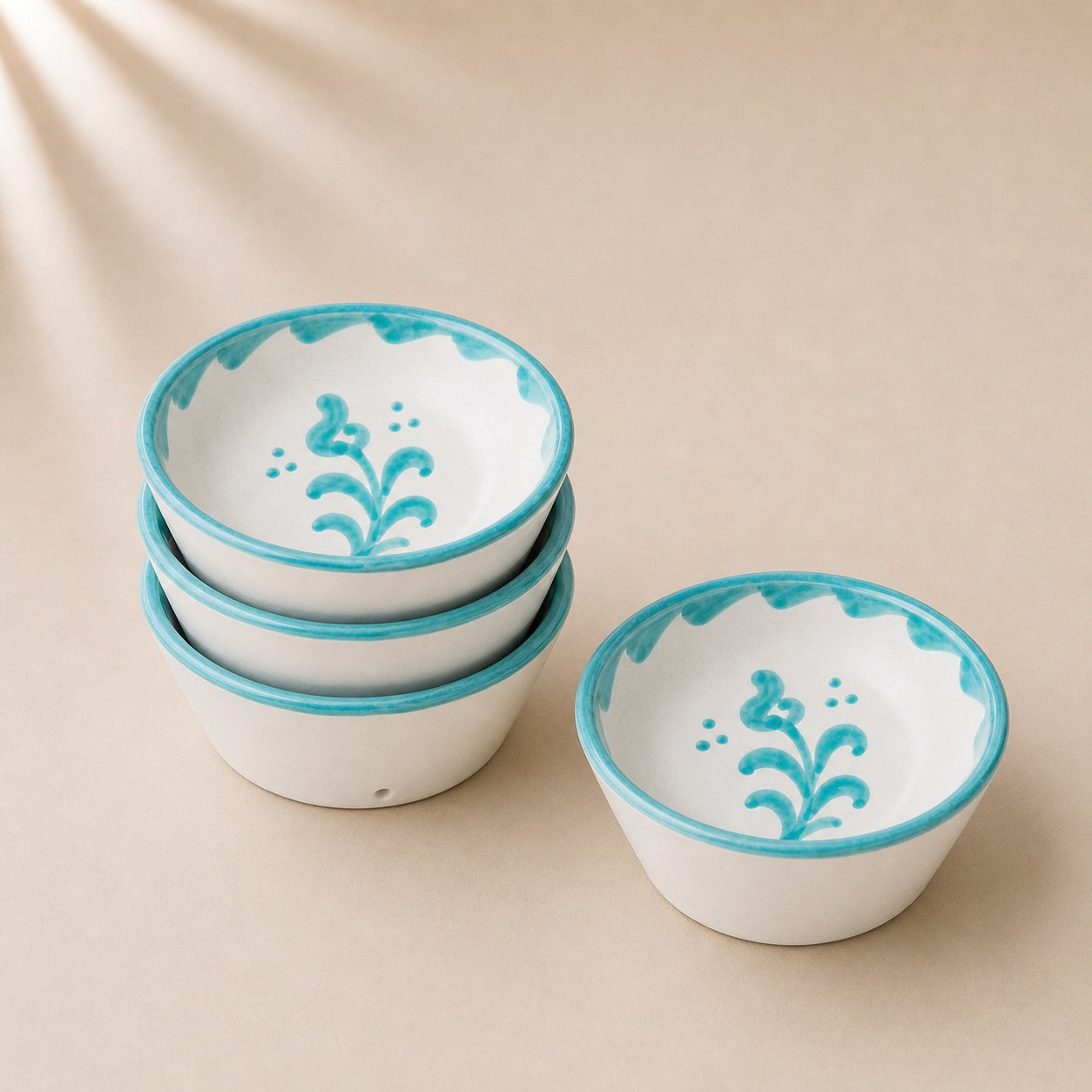 Set of ceramic bowls with turquoise rims and floral designs on a beige background