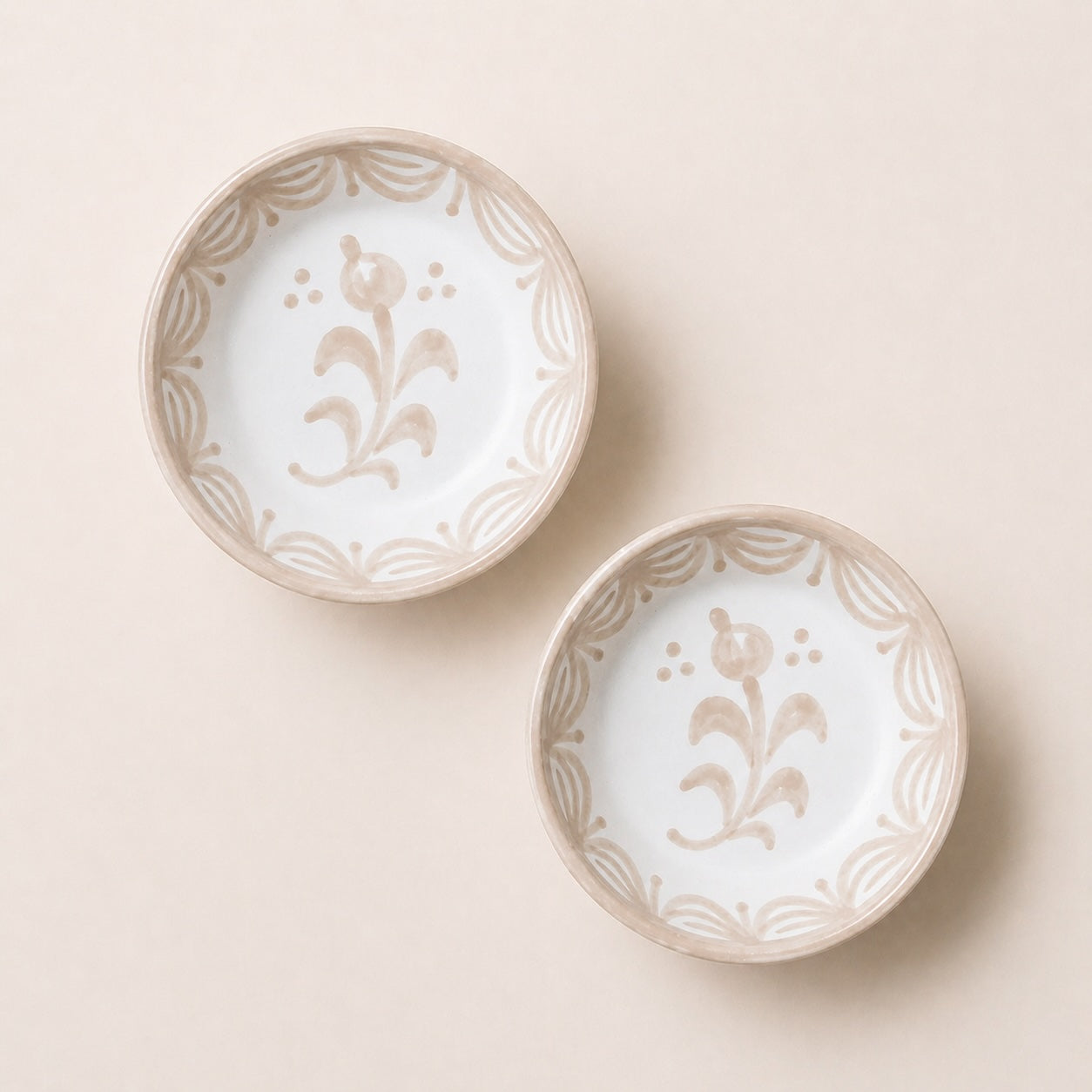Two ceramic bowls with floral patterns on a beige background