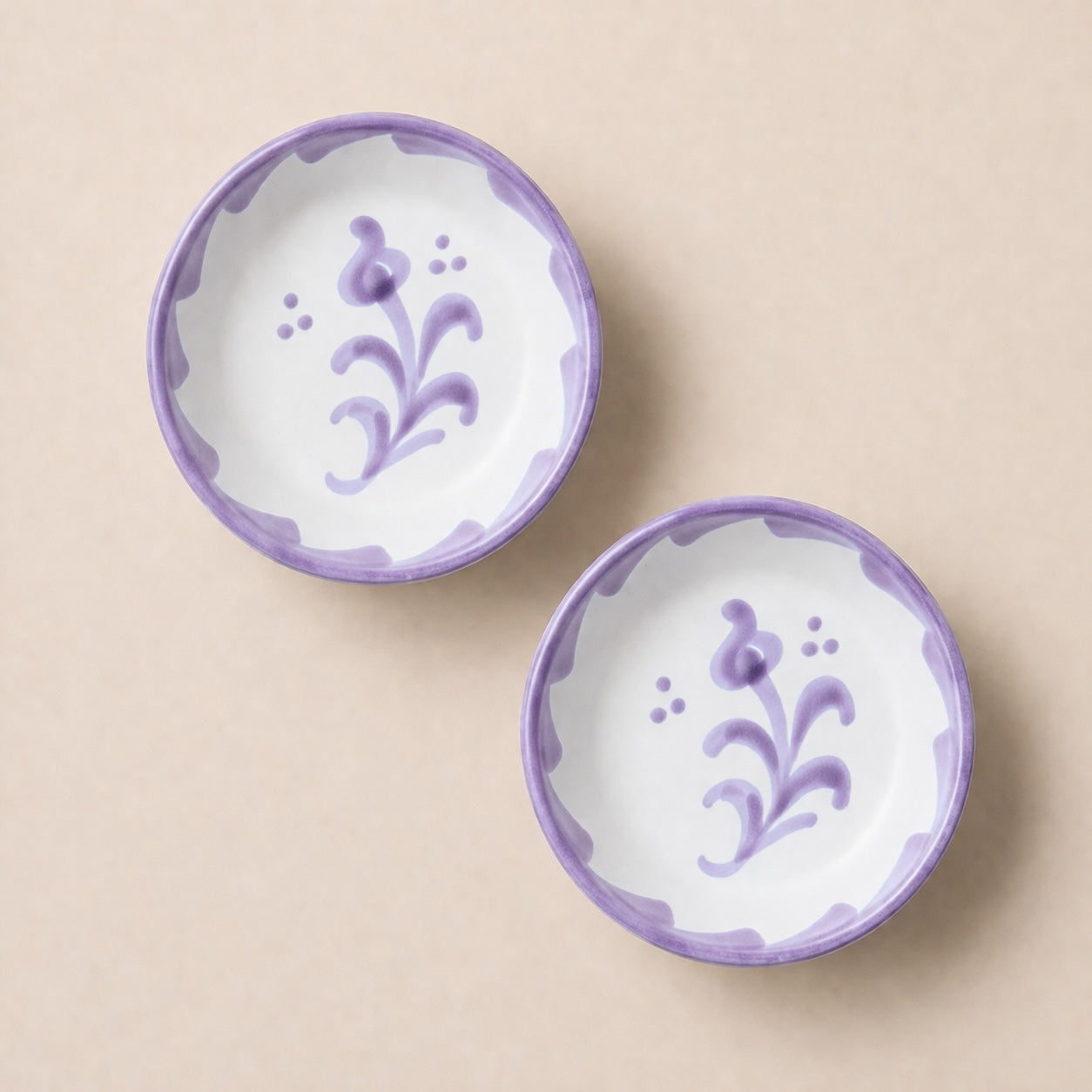 Two ceramic bowls with floral designs on a beige background