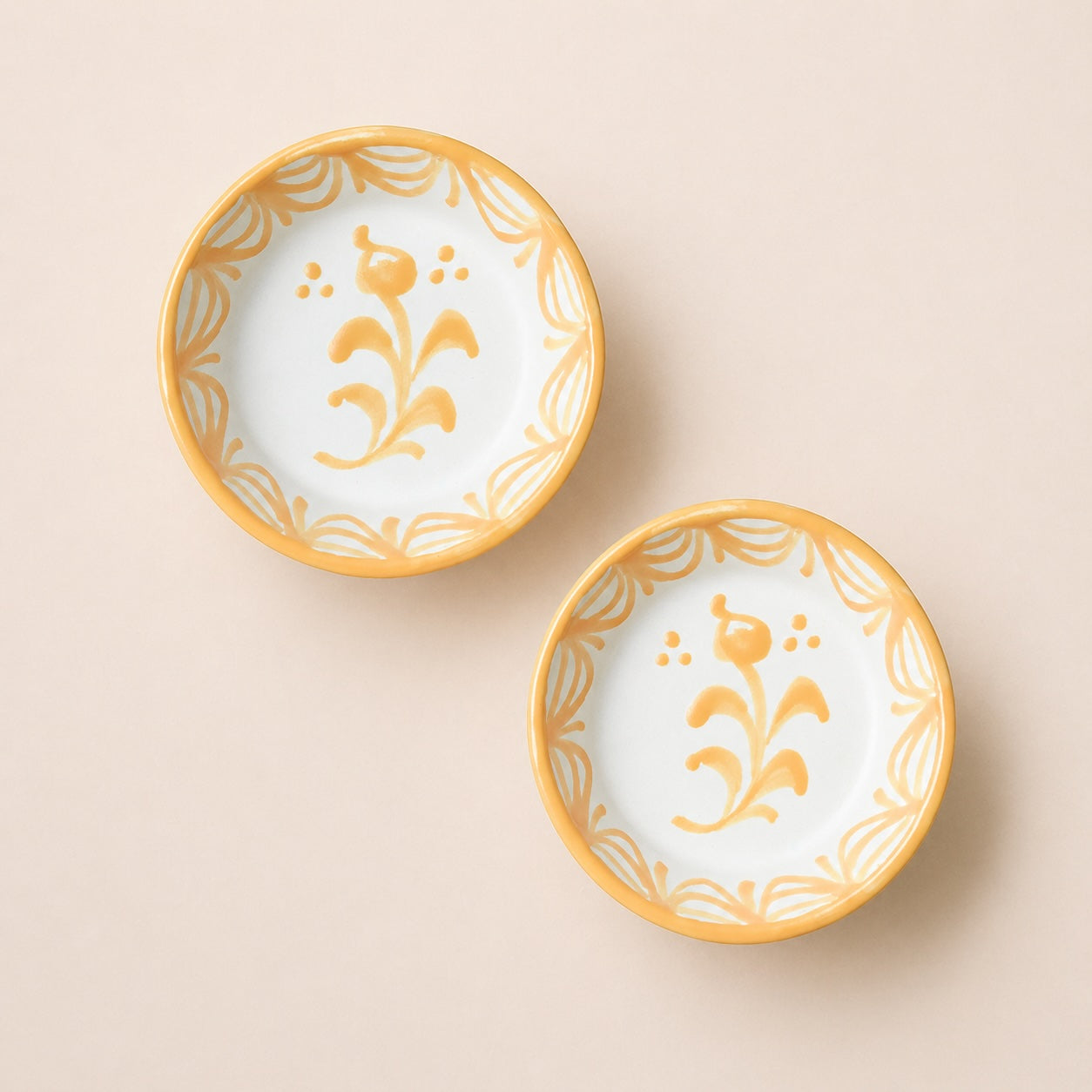 Two ceramic bowls with gold floral patterns on a beige background