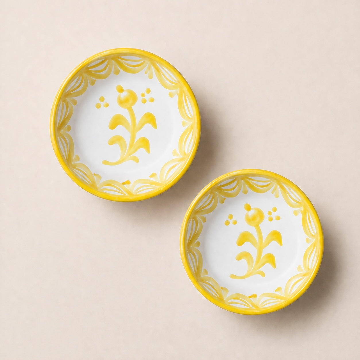 Two ceramic bowls with yellow floral patterns on a beige background