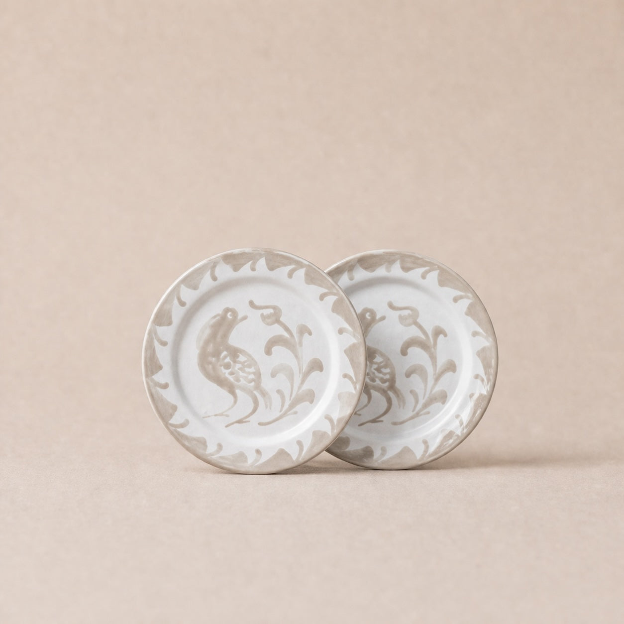 Two ceramic plates with decorative patterns on a beige background
