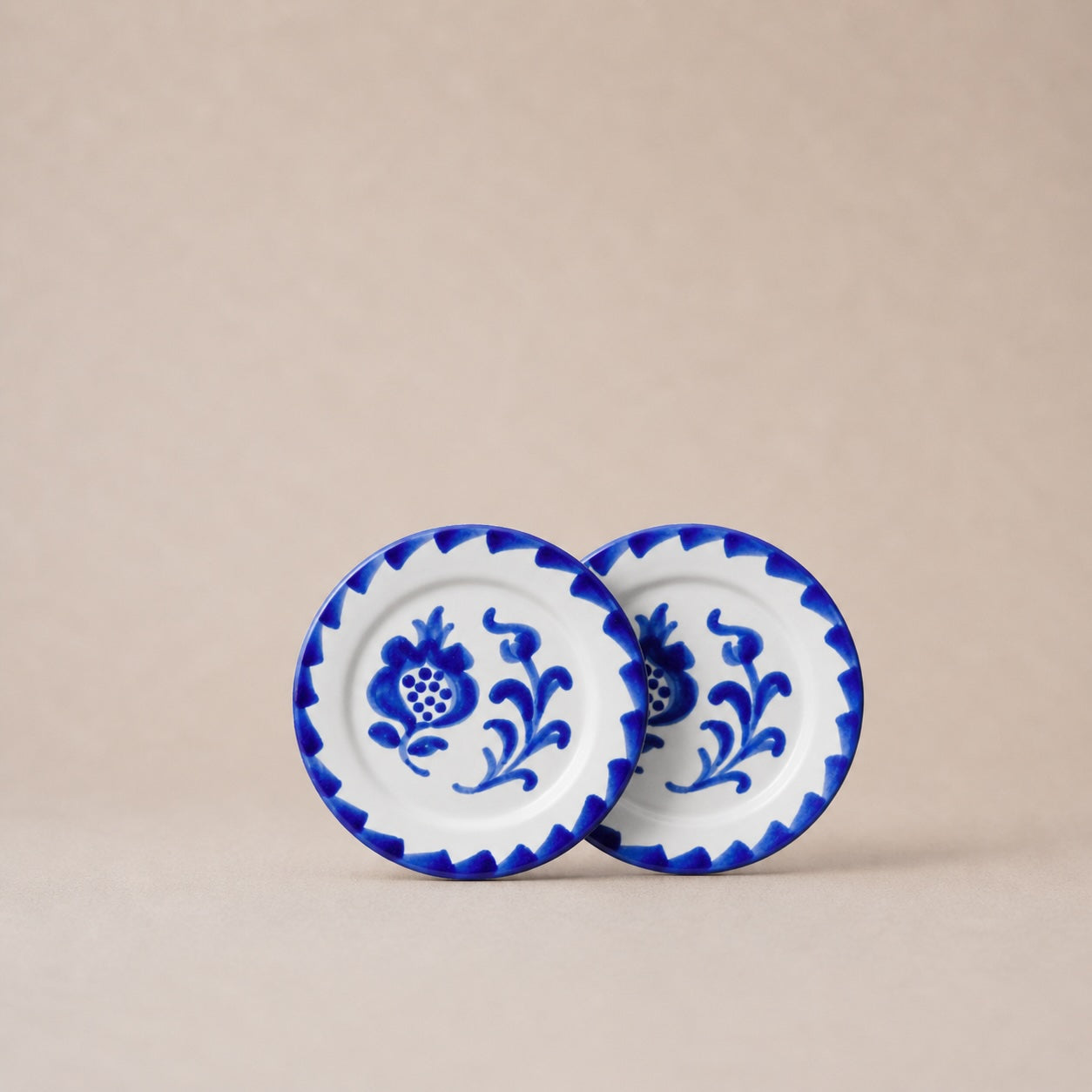 Two ceramic plates with blue floral patterns on a beige background