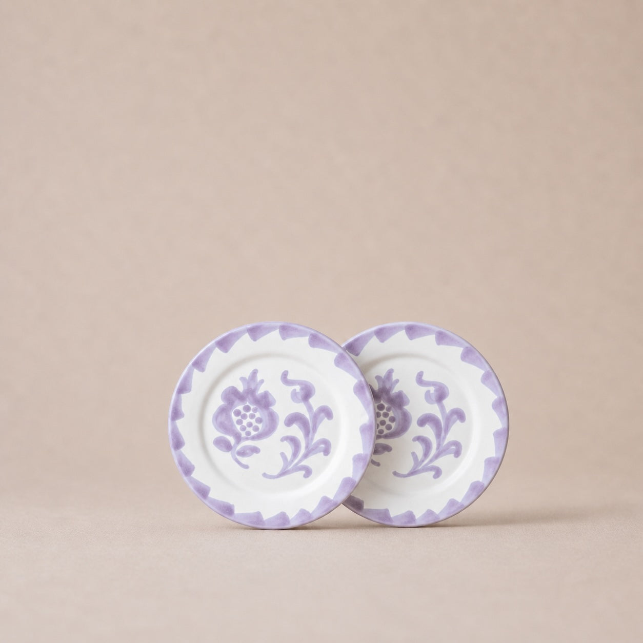 Two ceramic plates with purple floral patterns on a beige background