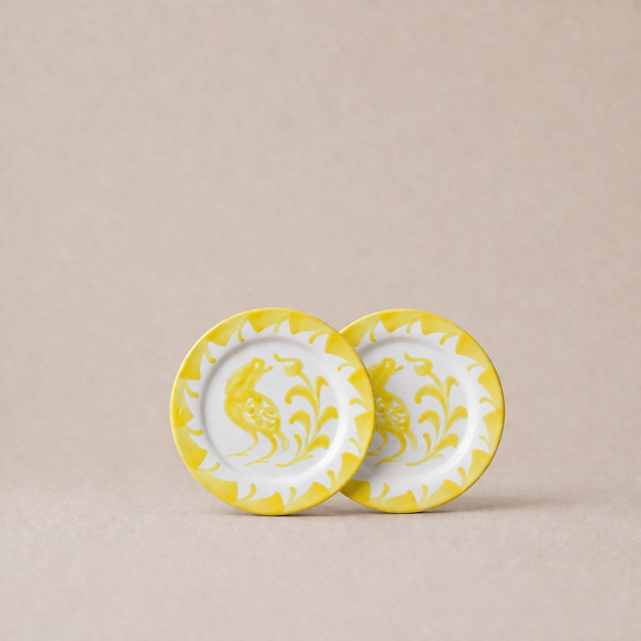 Two ceramic plates with yellow floral patterns on a beige background