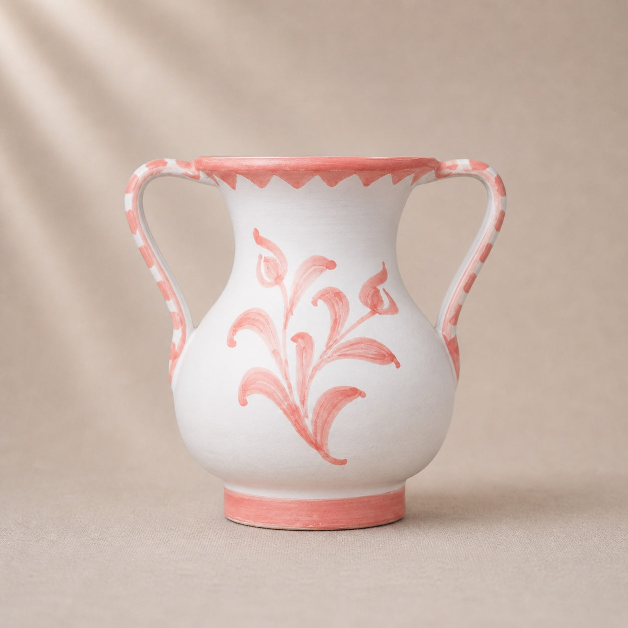 White ceramic vase with pink floral patterns on a beige background