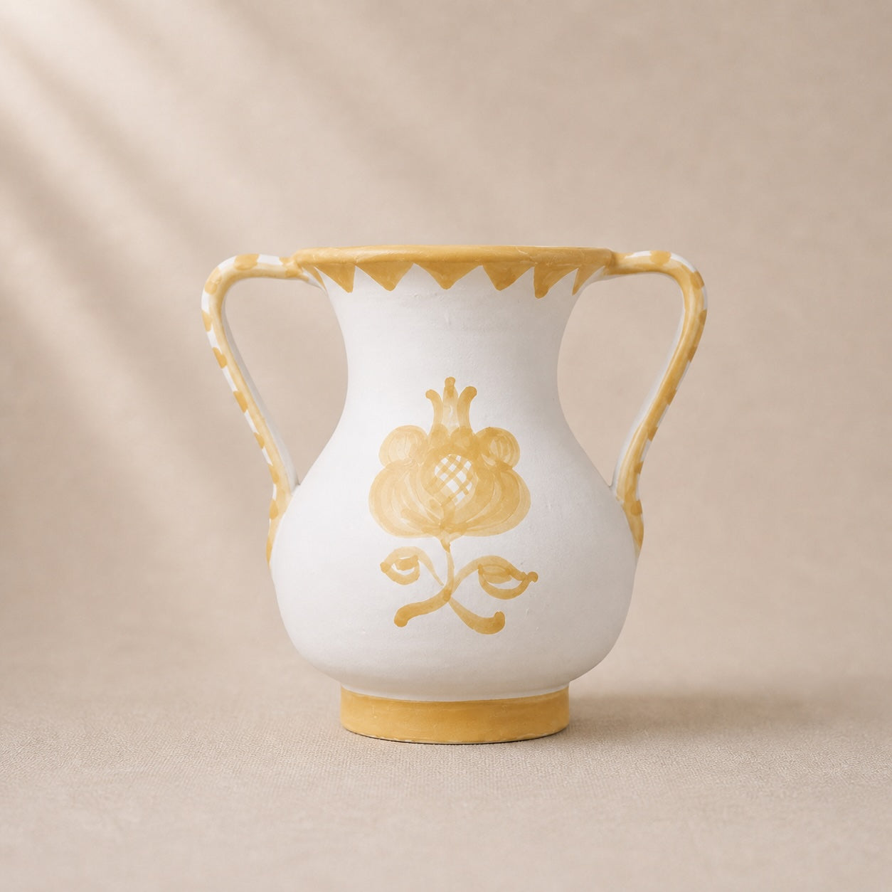 White vase with gold floral design and trim on a beige background