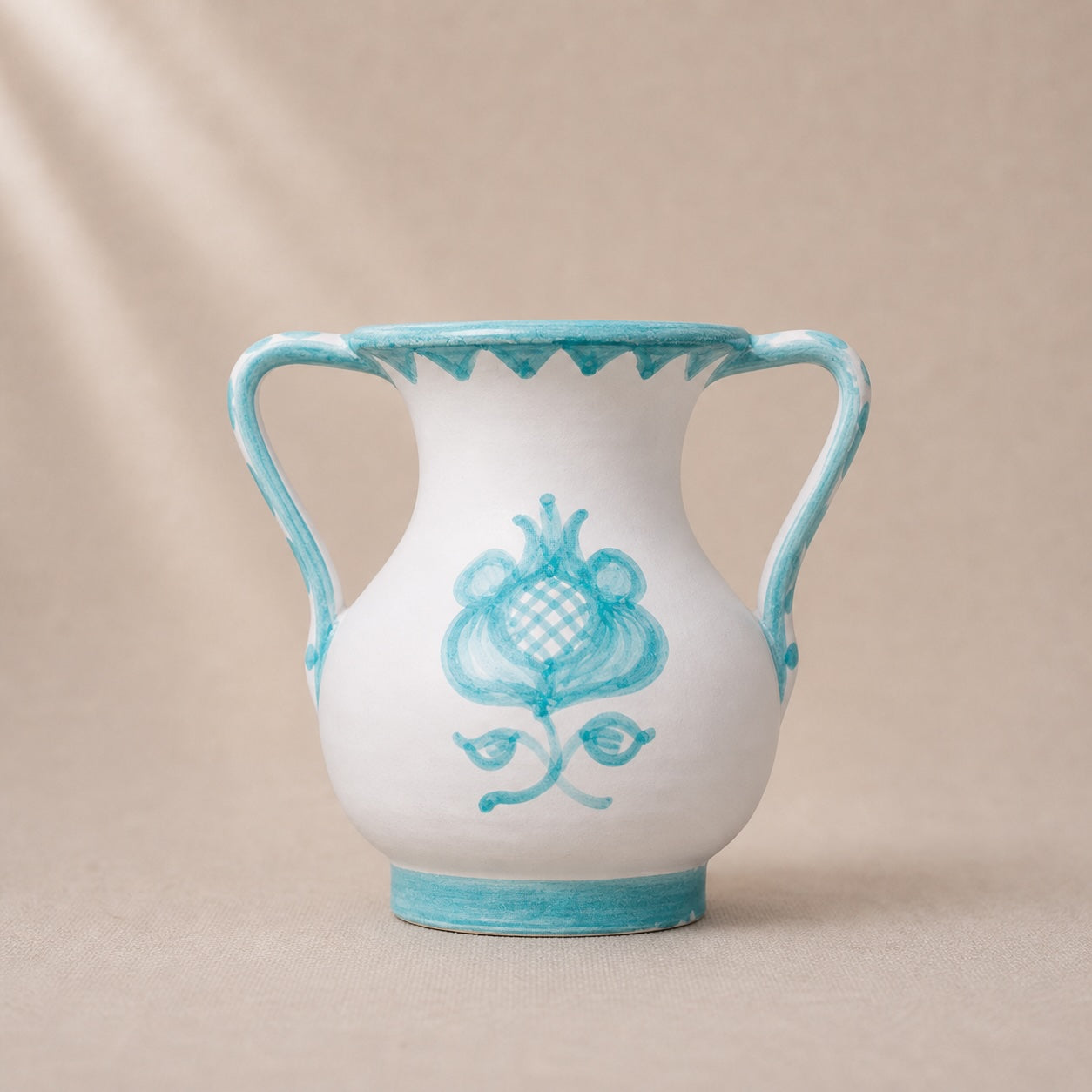 White vase with blue floral design and rim on a beige background