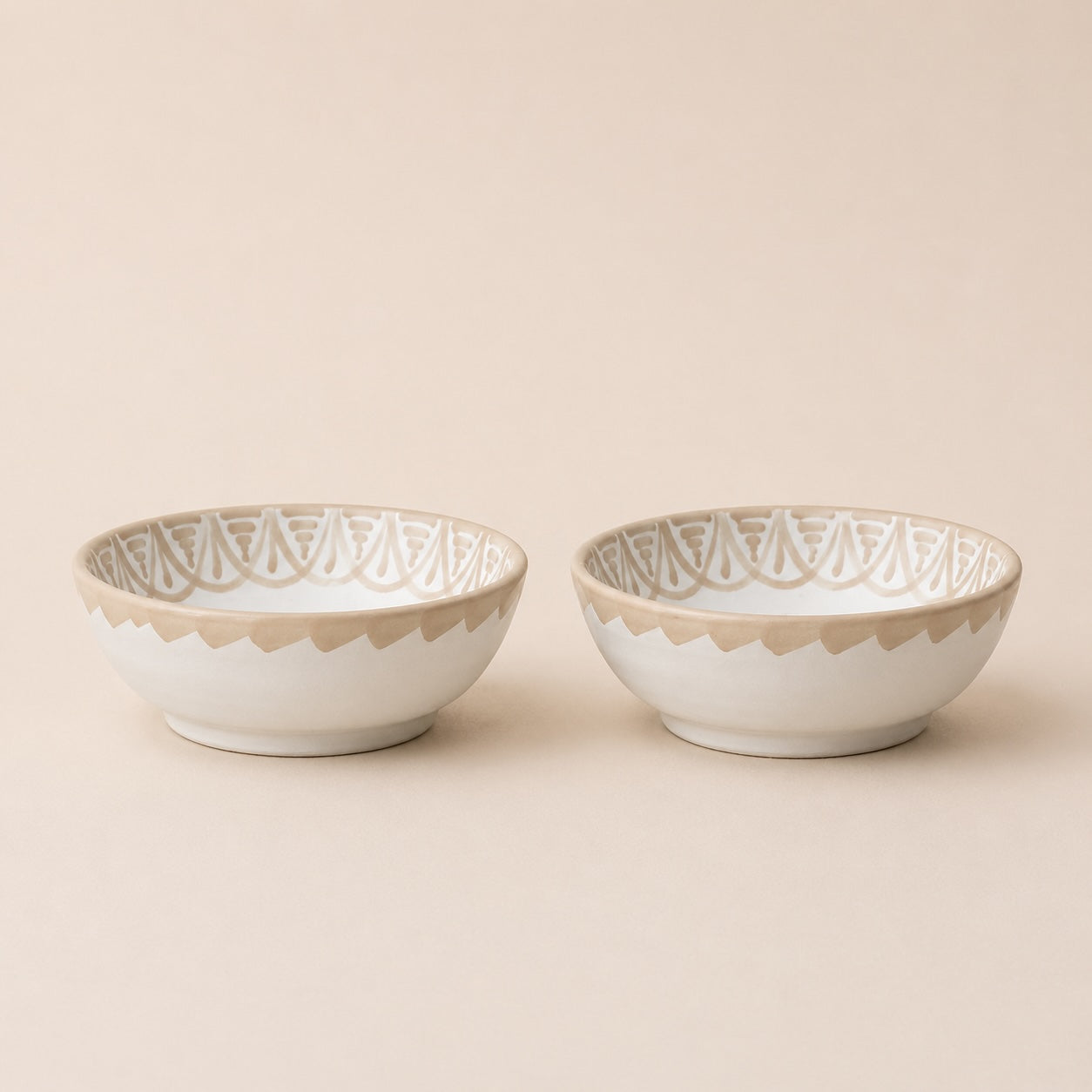 Two ceramic bowls with decorative patterns on a beige background