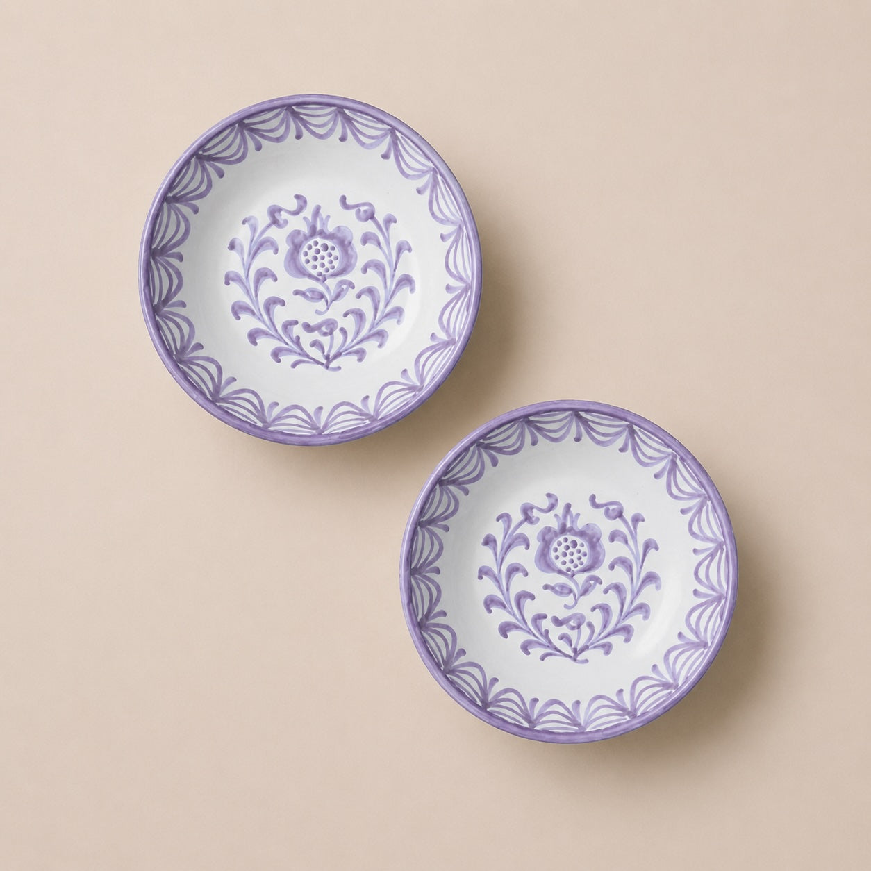 Two ceramic bowls with purple floral patterns on a beige background