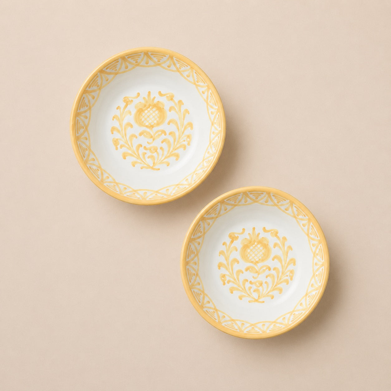 Two ceramic plates with yellow floral patterns on a beige background