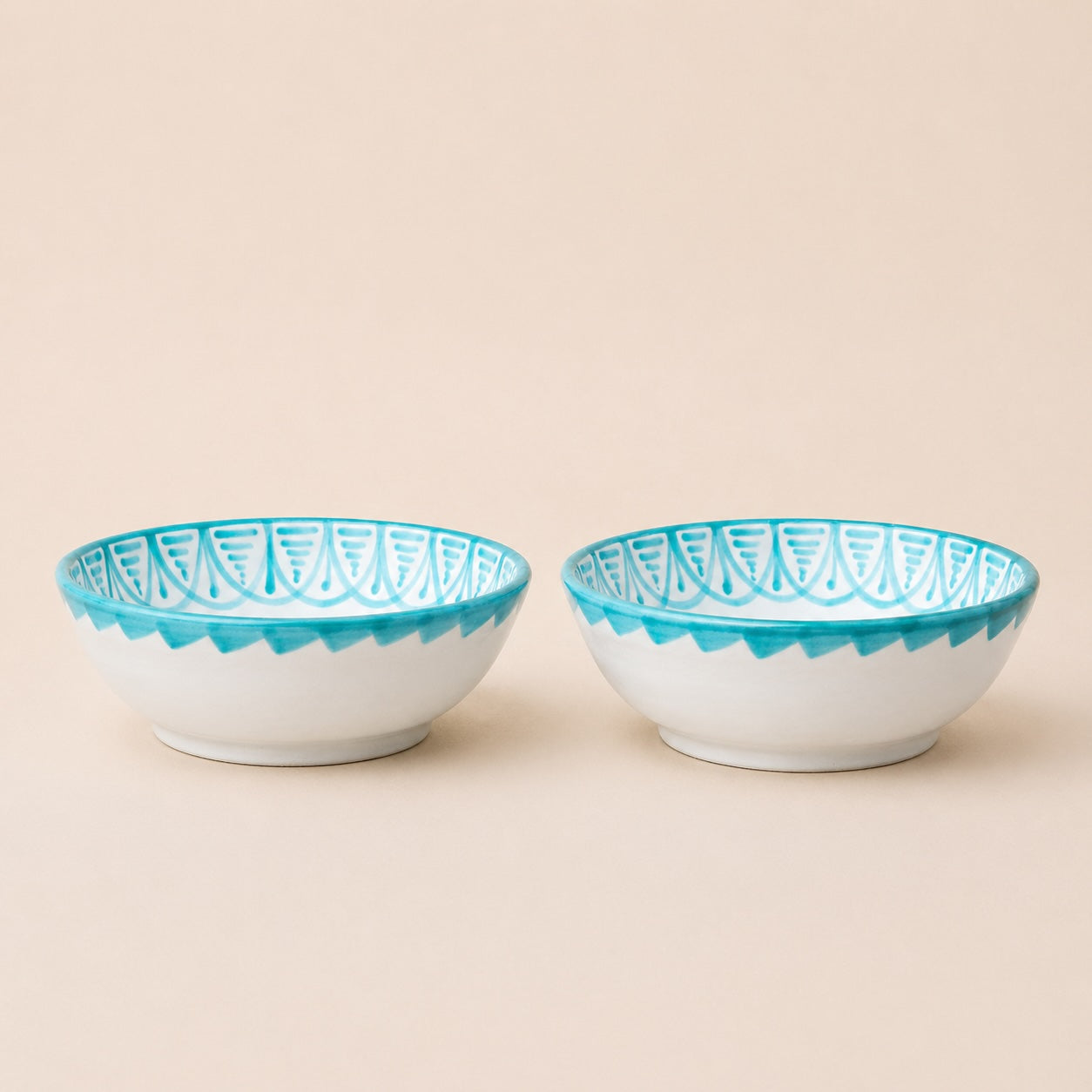 Two ceramic bowls with blue decorative rims on a beige background