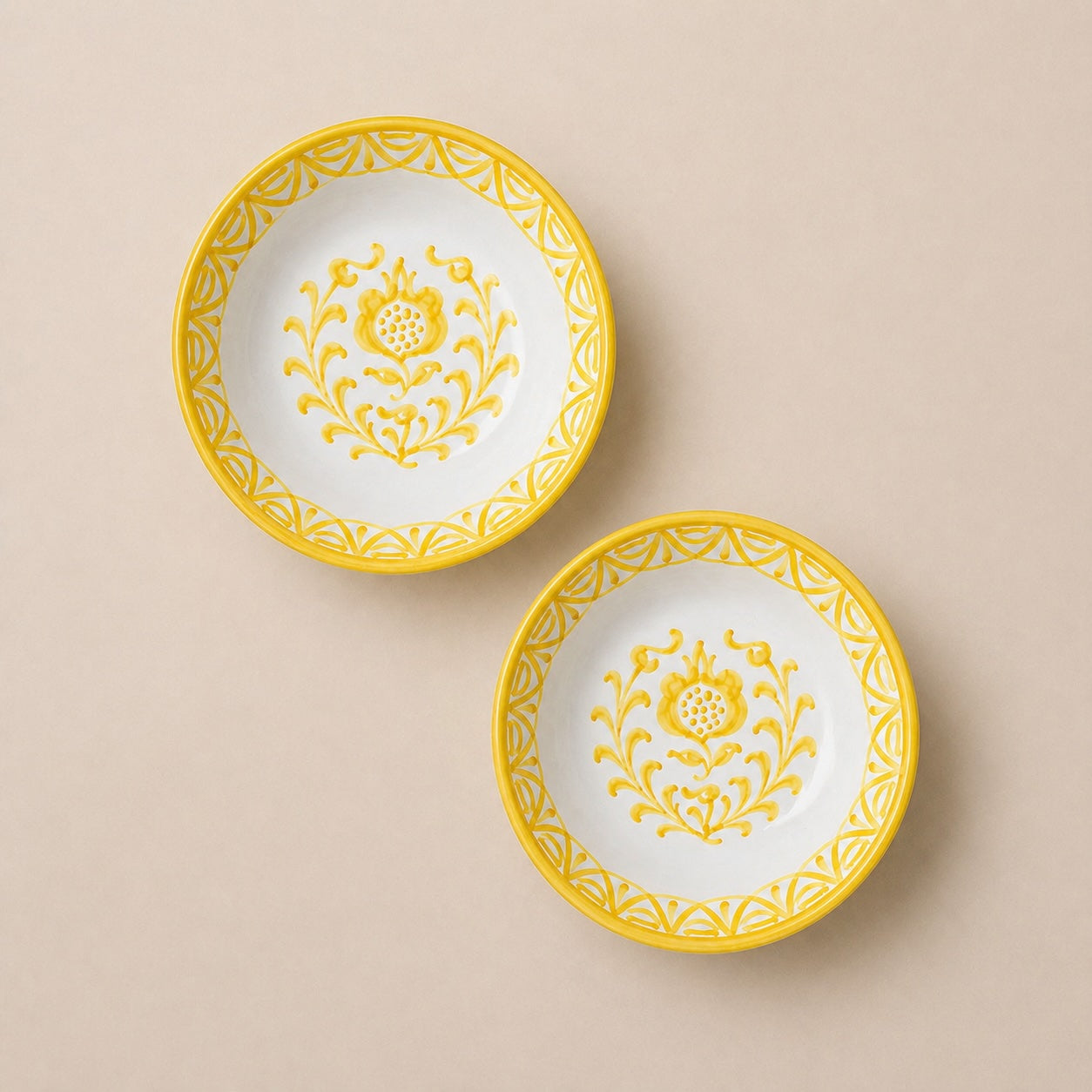Two white plates with yellow floral patterns on a beige background