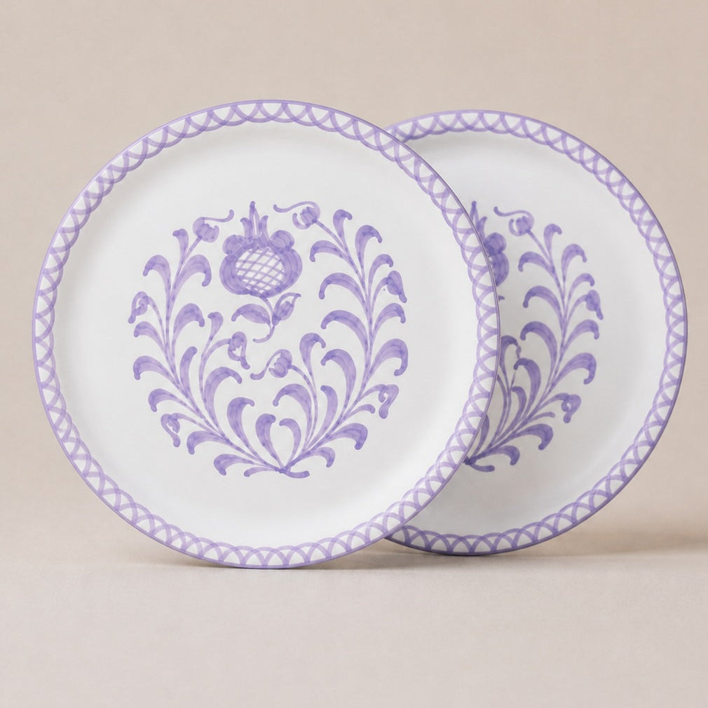 Two decorative traditional dinner plates with lilac floral patterns on a beige background