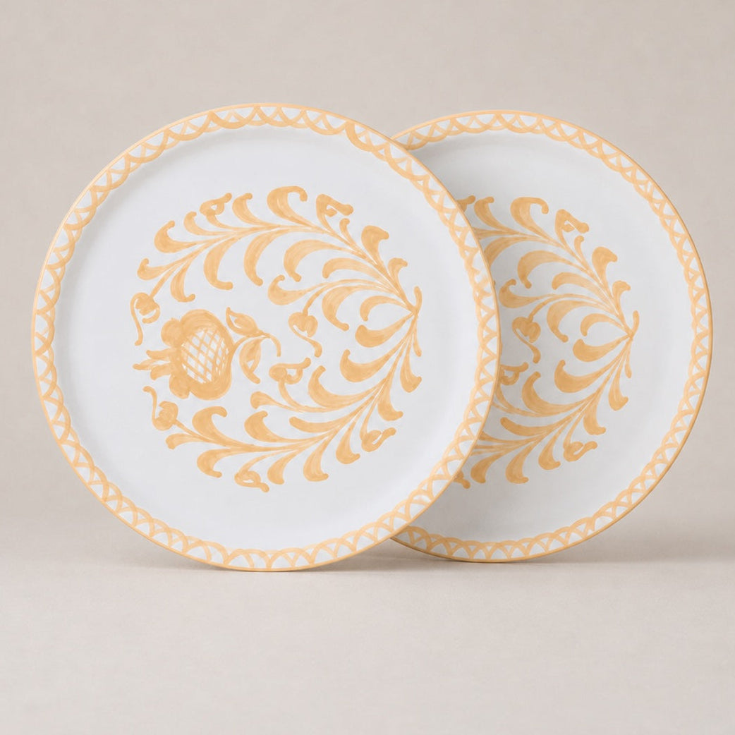 Two decorative traditional dinnerl plates with gold floral patterns on a beige background