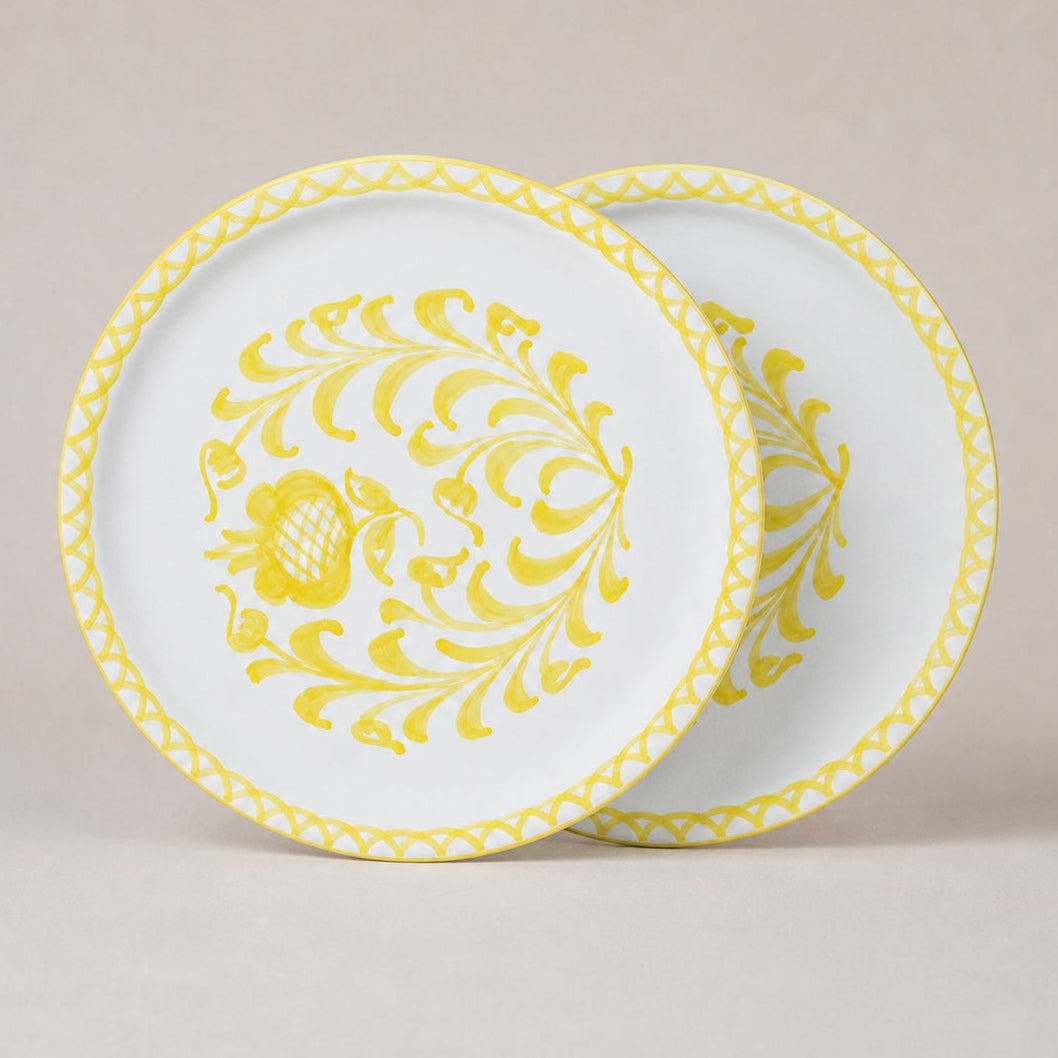 Two traditional dinner plates with yellow floral patterns on a beige background