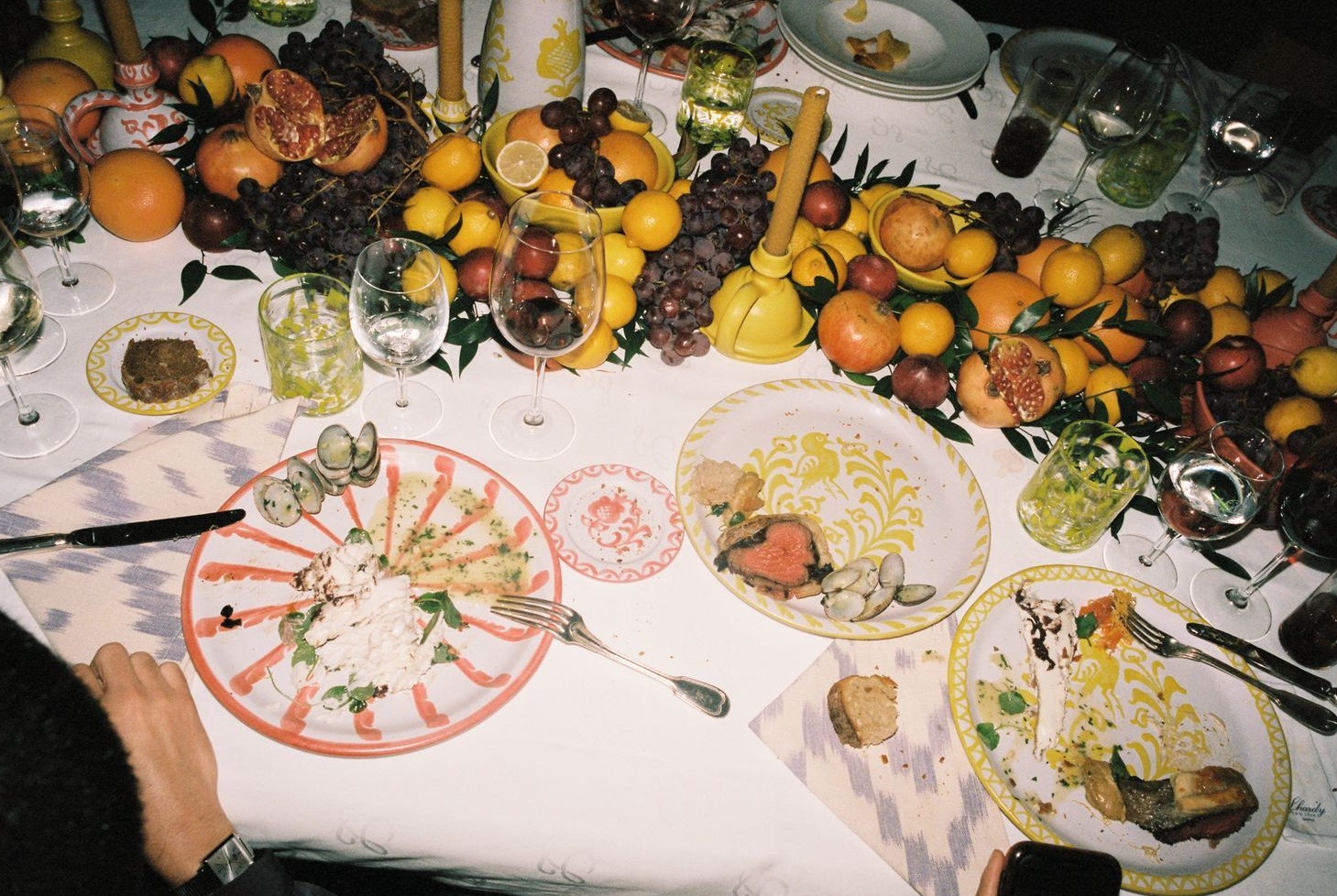 Dinner table set with plates, cutlery, and a variety of fruits and vegetables.