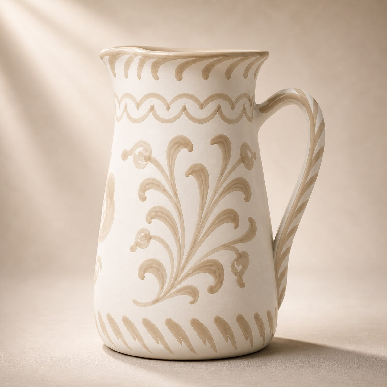 White ceramic pitcher with beige floral patterns on a beige background