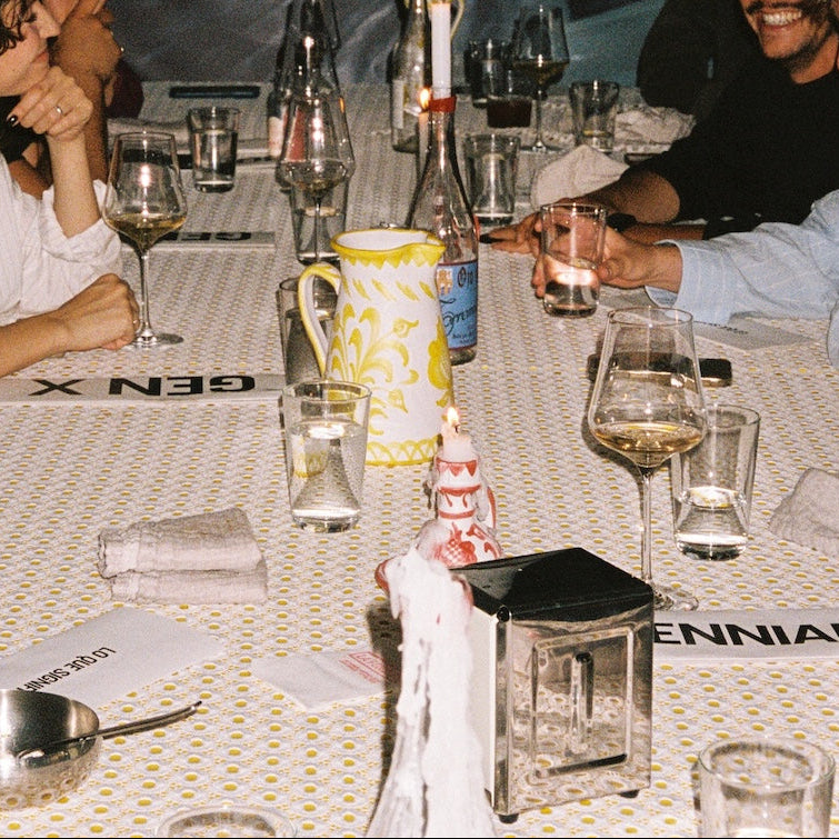 People sitting around a table with wine glasses and a pitcher, with 'GEN X' and 'ENNIA' branding visible. - lifestyle