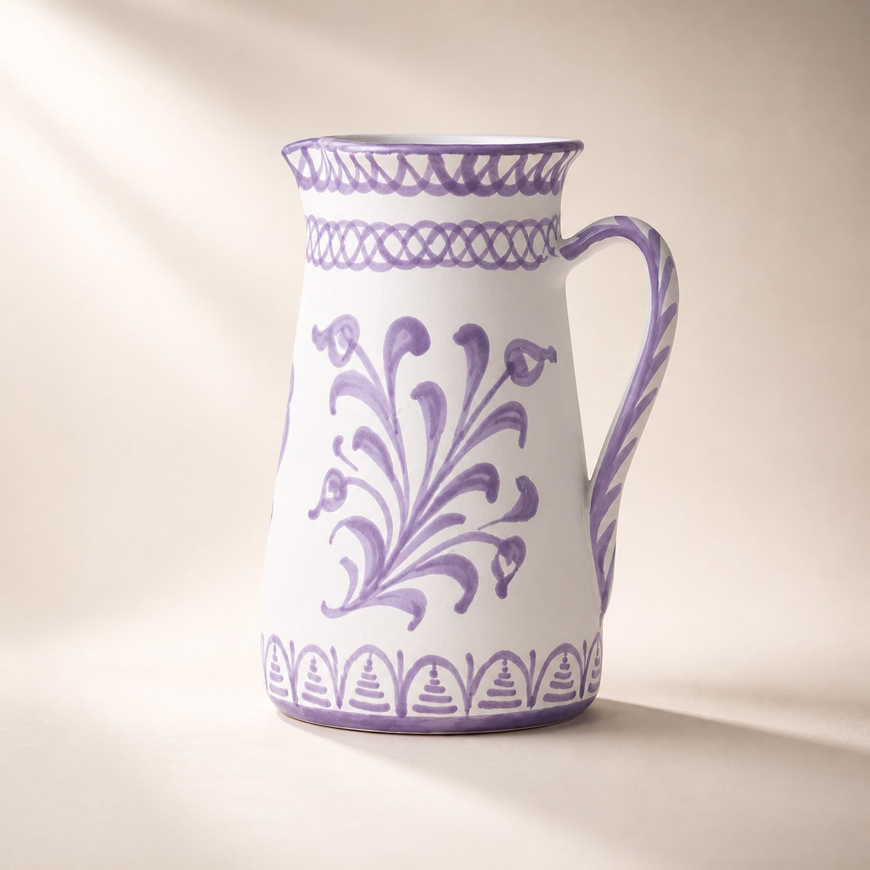 White ceramic pitcher with purple floral patterns on a beige background