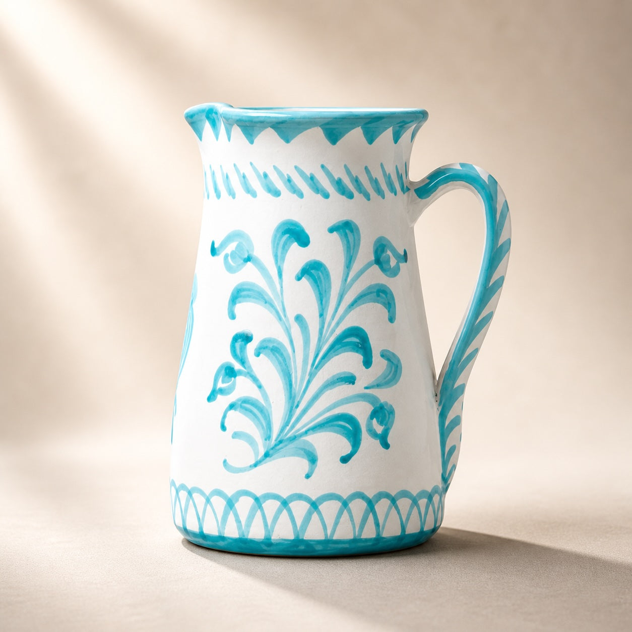 White ceramic pitcher with blue floral patterns on a beige background