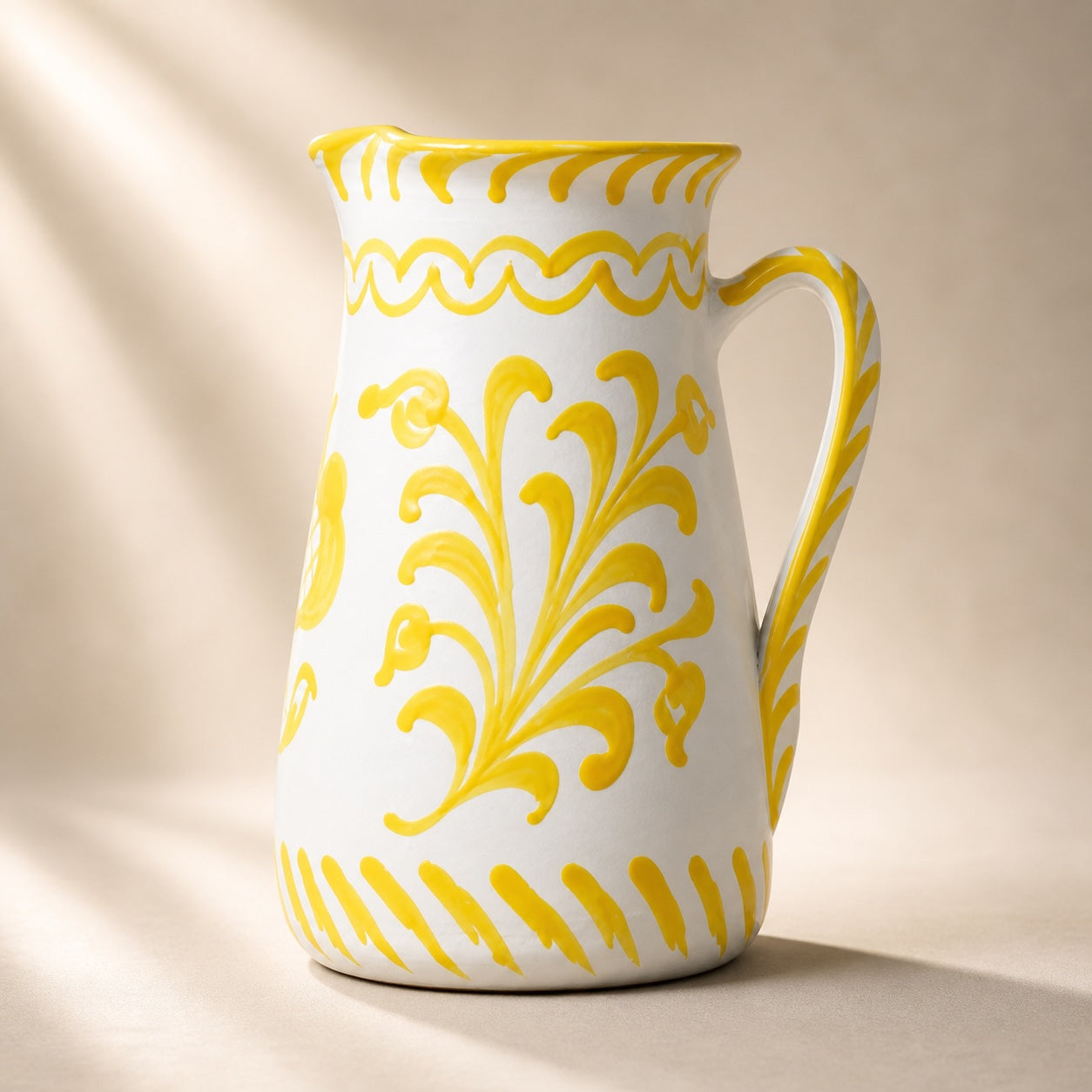 White ceramic pitcher with yellow floral patterns on a beige background